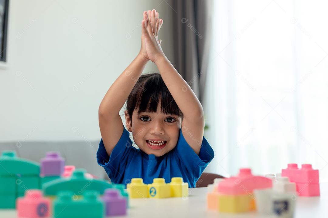 Menina asiática jogando blocos de brinquedo criativos para educação em casa