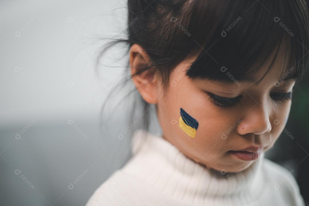 Uma criança com a bandeira da Ucrânia está chorando. Tristeza saudade esperança