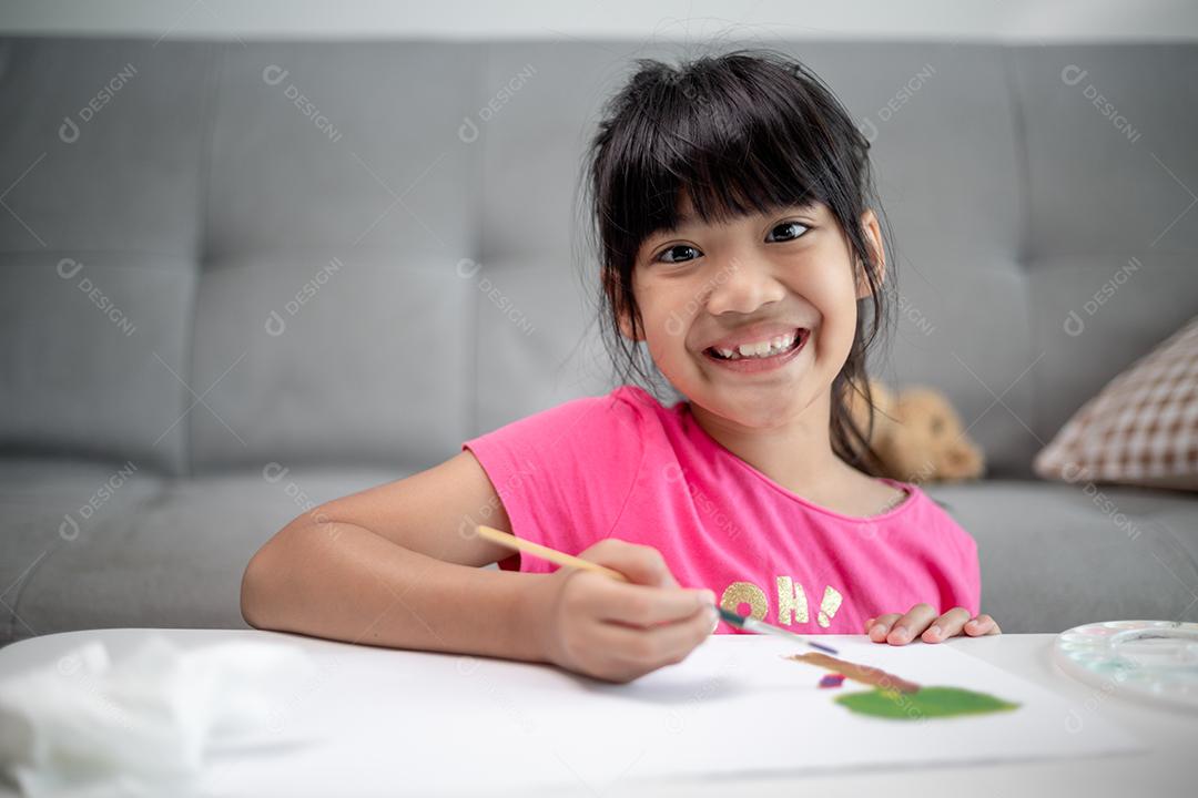 Menina pintando quadro na mesa em casa