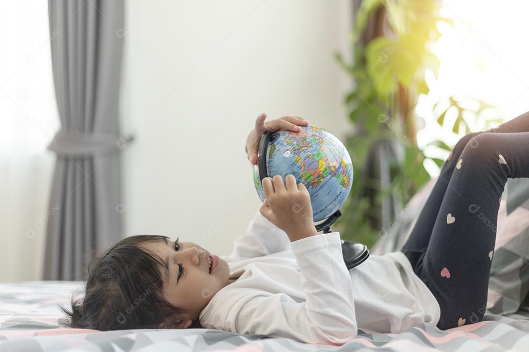 Linda garota olhando para um globo terrestre e aprendendo sobre geografia