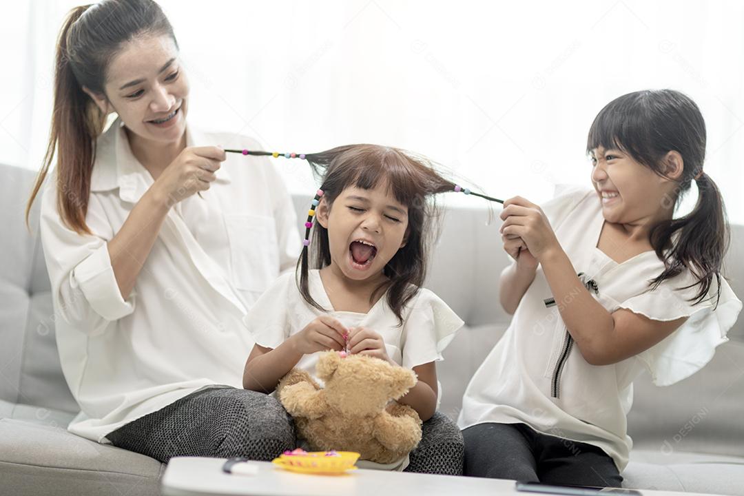 Jovem mãe asiática amarrando o cabelo da filha