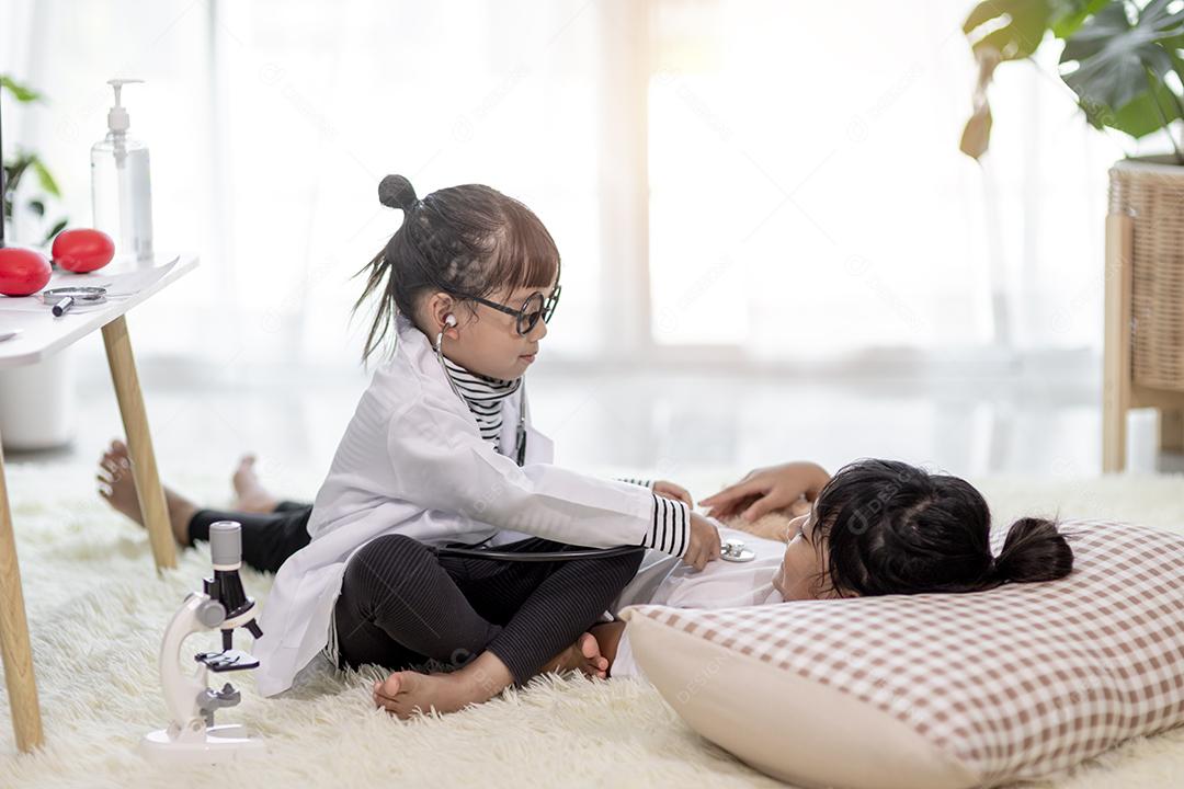 Duas crianças bonitas brincam de médico e hospital usando estetoscópio. Meninas de amigos se divertindo em casa ou pré-escola.