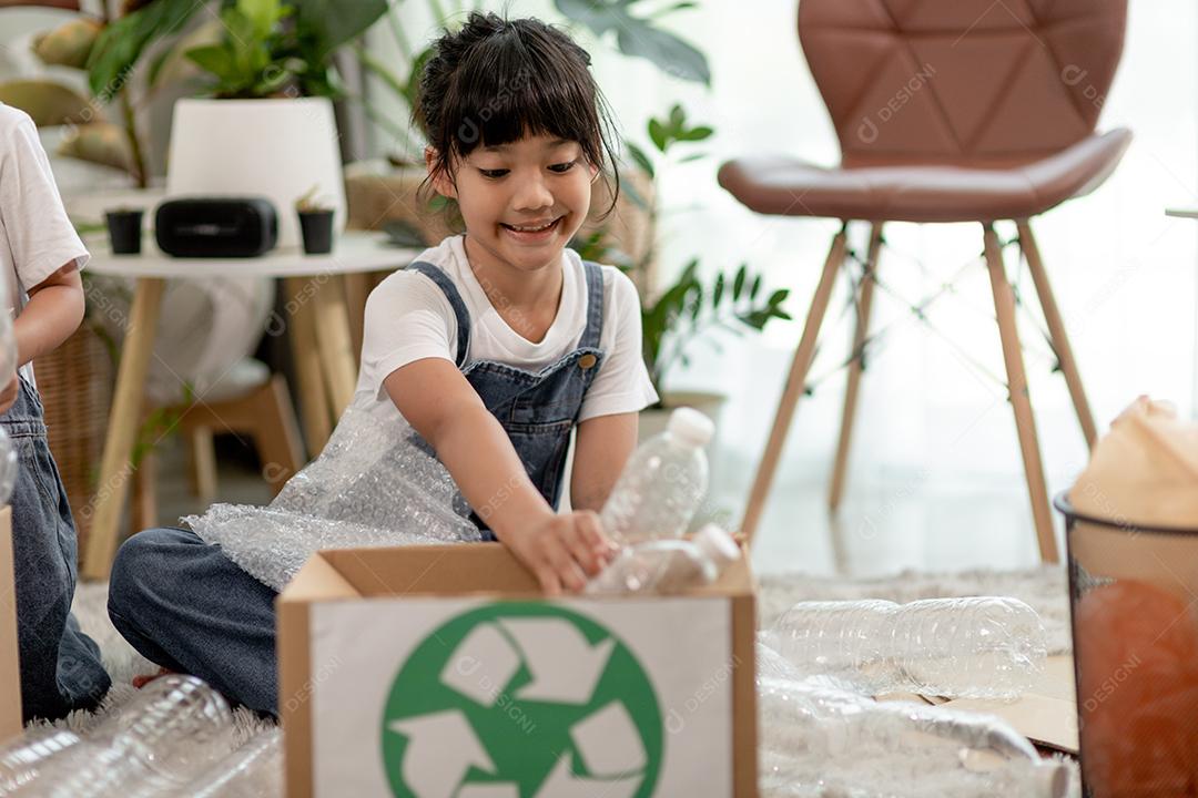 Crianças sorridentes se divertindo enquanto segregavam garrafas plásticas e papel em uma lixeira