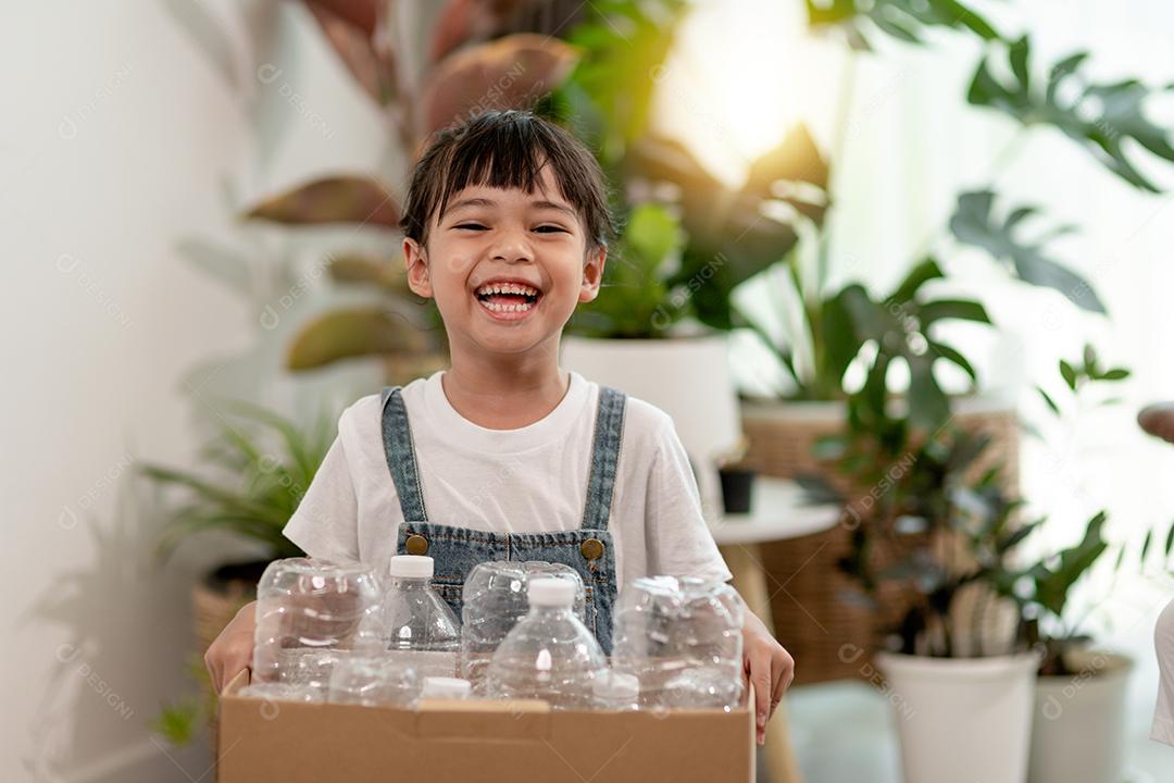 Garota olhando para a câmera e segurando garrafas plásticas para reciclagem