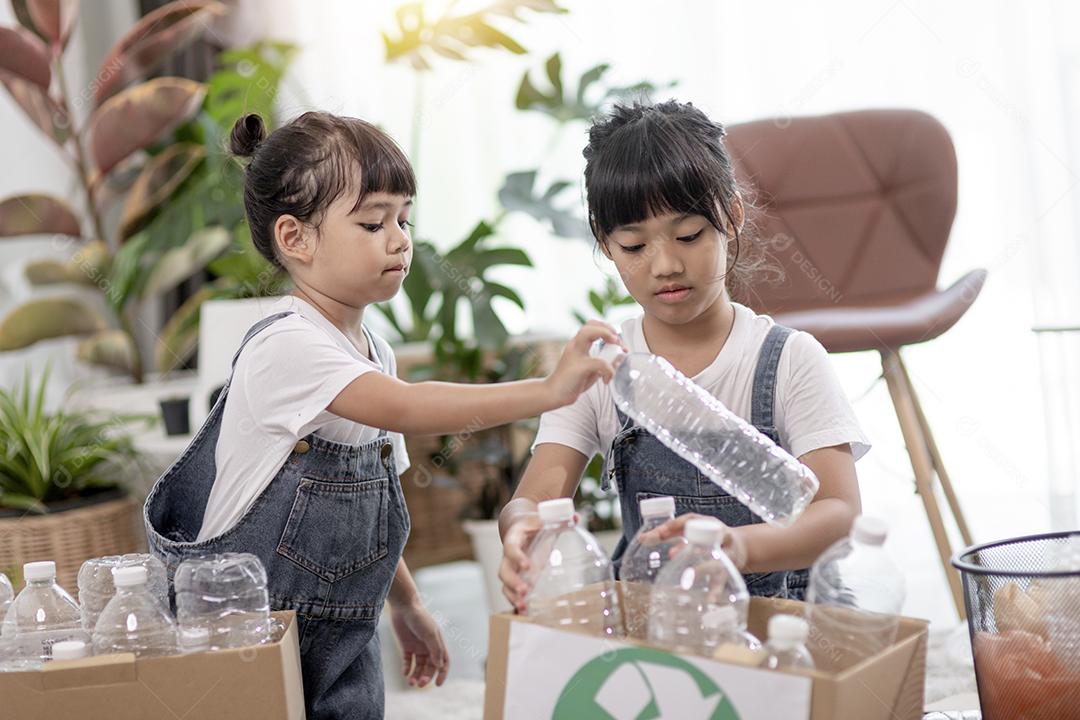 Crianças sorridentes se divertindo enquanto segregavam garrafas plásticas e papel em uma lixeira