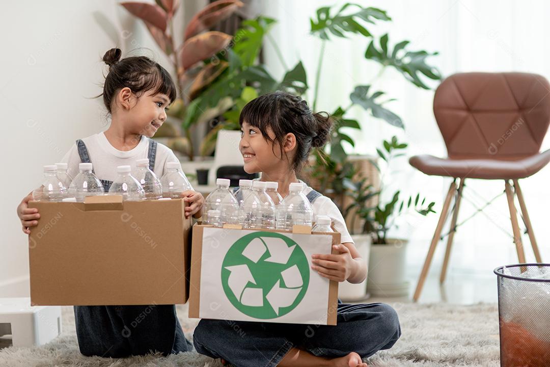 Crianças sorridentes se divertindo enquanto segregavam garrafas plásticas e papel em uma lixeira