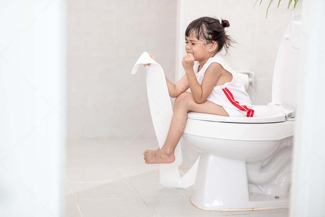 A garotinha está sentada no vaso sanitário sofrendo de constipação ou hemorroida.