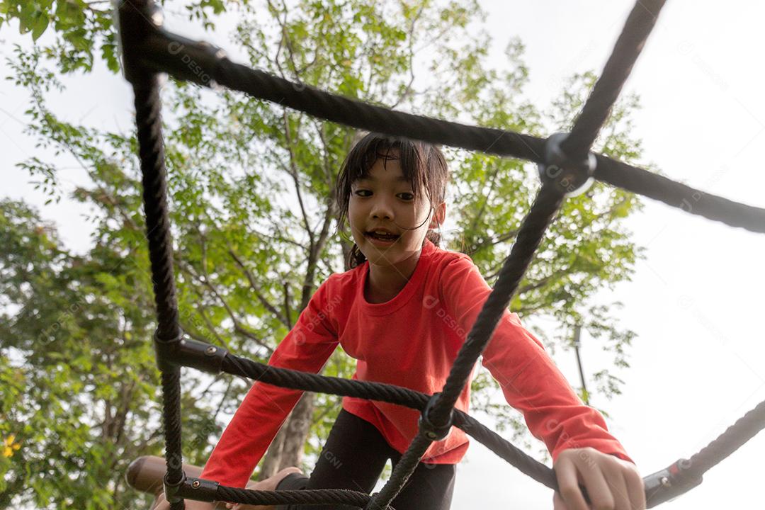 conceito de verão, infância, lazer e pessoas - menina feliz no quadro de escalada do parque infantil