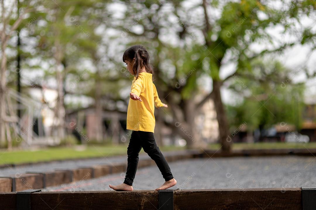 Menina asiática brincando no playground no parque ao ar livre Momento feliz e boa emoção