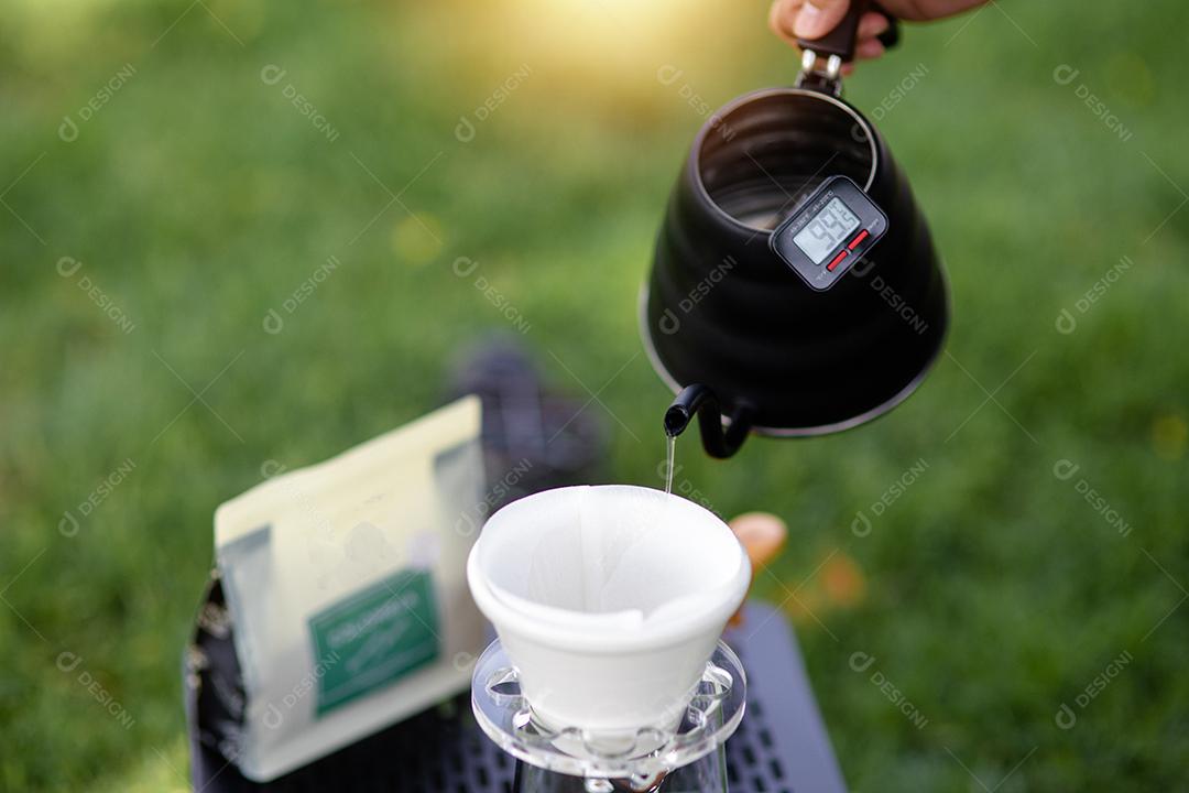 Jovem derramando café na xícara, café da manhã ao ar livre. viajante acampando pela primeira vez, nova experiência para descansar com barraca. Natureza, lazer, sem pressa, conceito de paz e tranquilidade