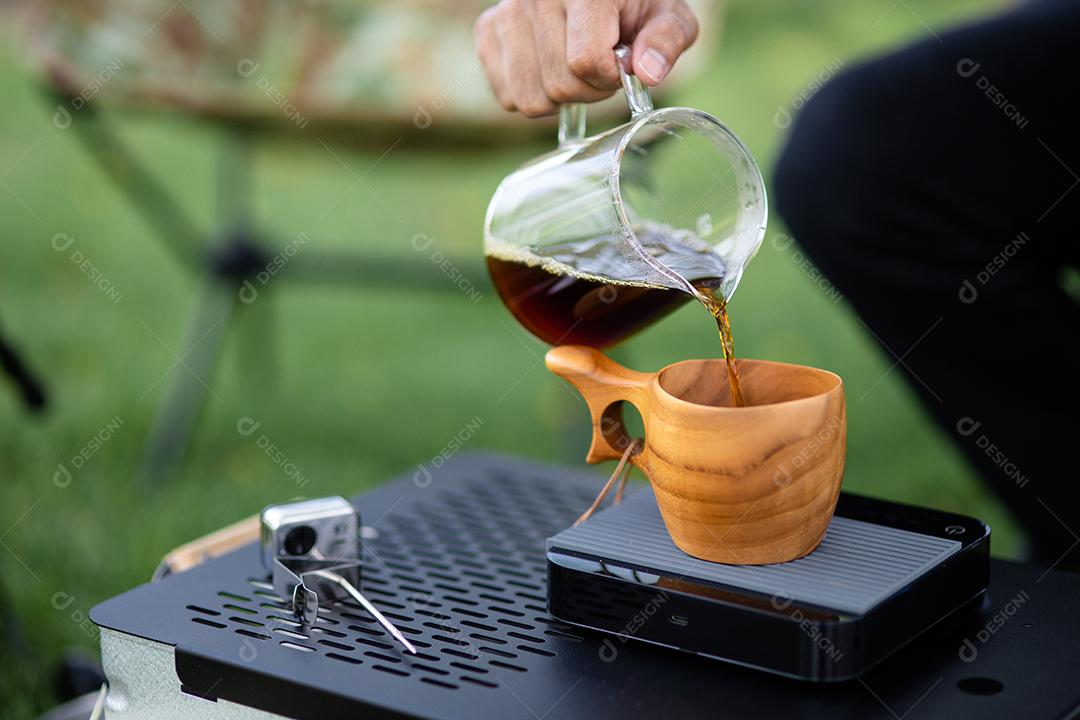 Jovem derramando café na xícara, café da manhã ao ar livre. viajante acampando pela primeira vez, nova experiência para descansar com barraca. Natureza, lazer, sem pressa, conceito de paz e tranquilidade