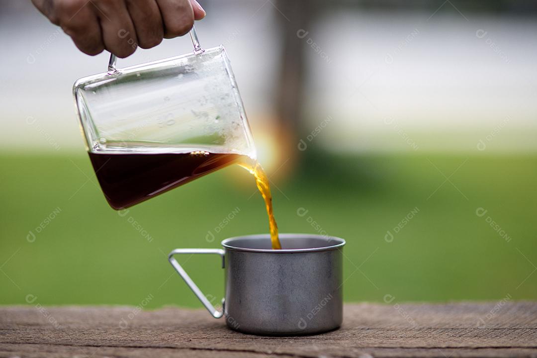 Jovem derramando café na xícara, café da manhã ao ar livre. viajante acampando pela primeira vez, nova experiência para descansar com barraca. Natureza, lazer, sem pressa, conceito de paz e tranquilidade