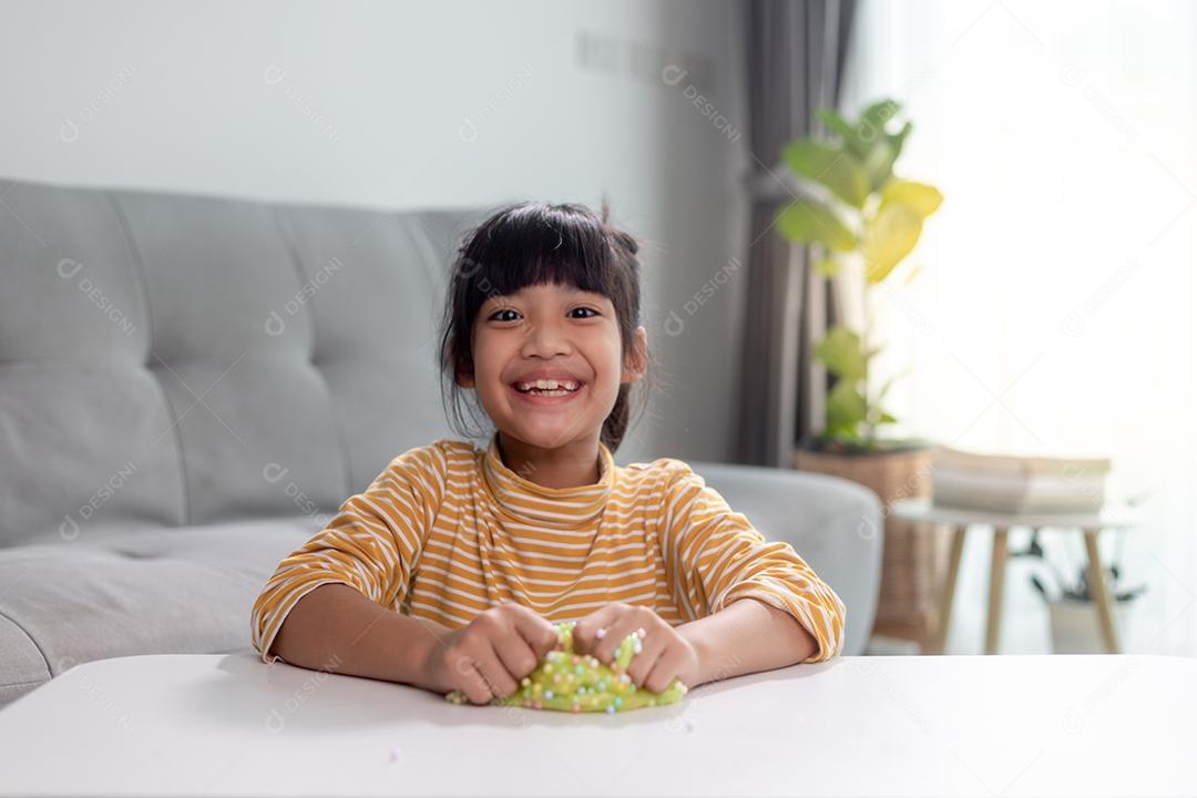 A garotinha está aprendendo a usar massinha colorida em uma sala bem iluminada