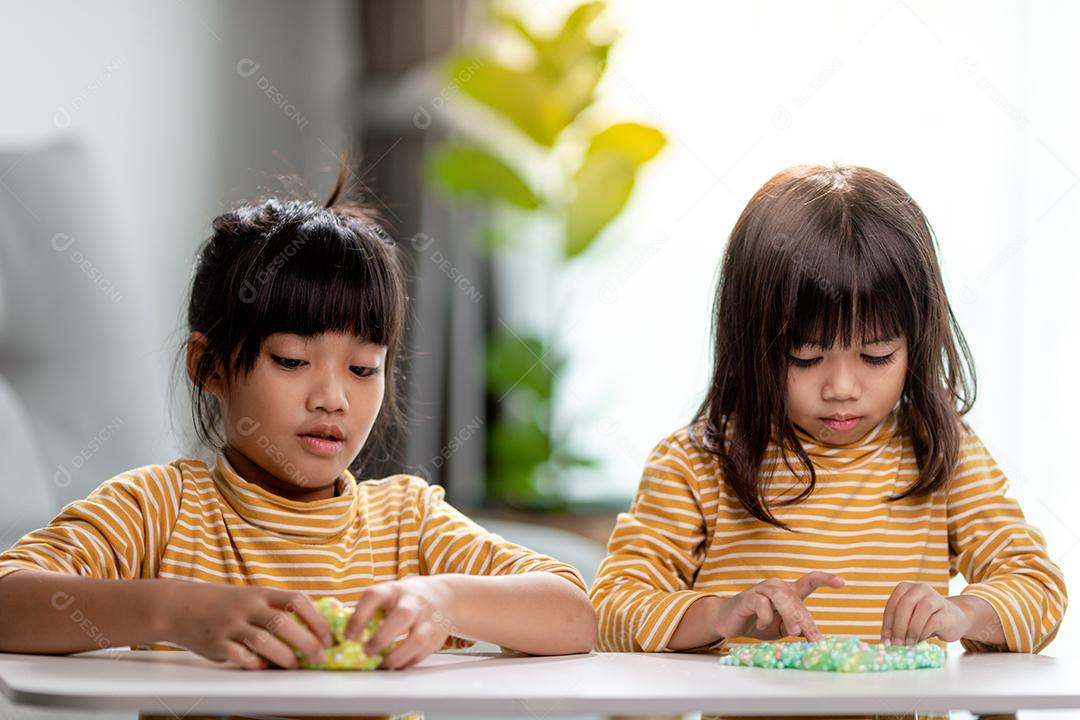 A garotinha está aprendendo a usar massinha colorida em uma sala bem iluminada