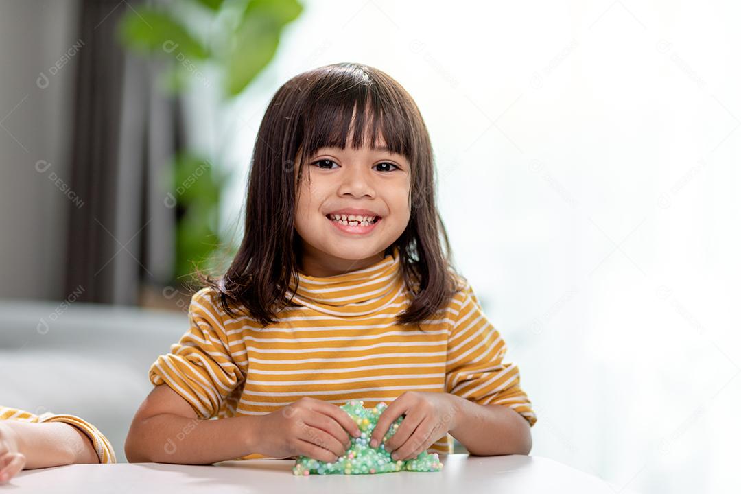 A garotinha está aprendendo a usar massinha colorida em uma sala bem iluminada