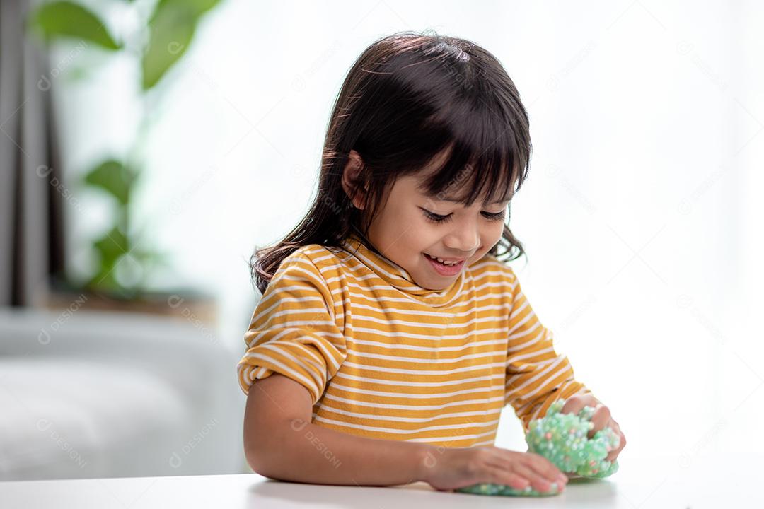 A garotinha está aprendendo a usar massinha colorida em uma sala bem iluminada