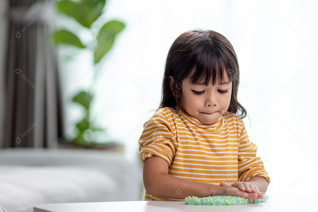 A garotinha está aprendendo a usar massinha colorida em uma sala bem iluminada