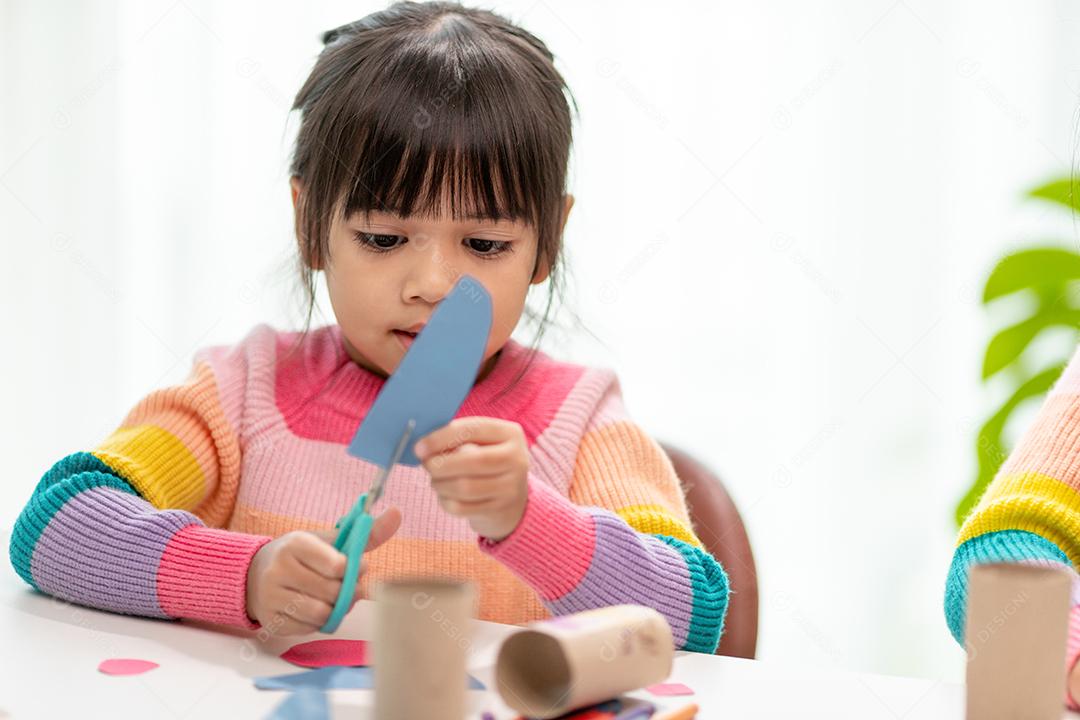 Retrato de uma menina asiática cortando um papel em atividades na aula de bricolage na School.Scissors corta papel.