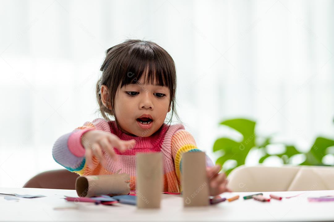 Meninas asiáticas estão fazendo binóculos de papel de seda. Reutilize produtos residuais. Idéia de brinquedo feito sob encomenda. Foco suave.