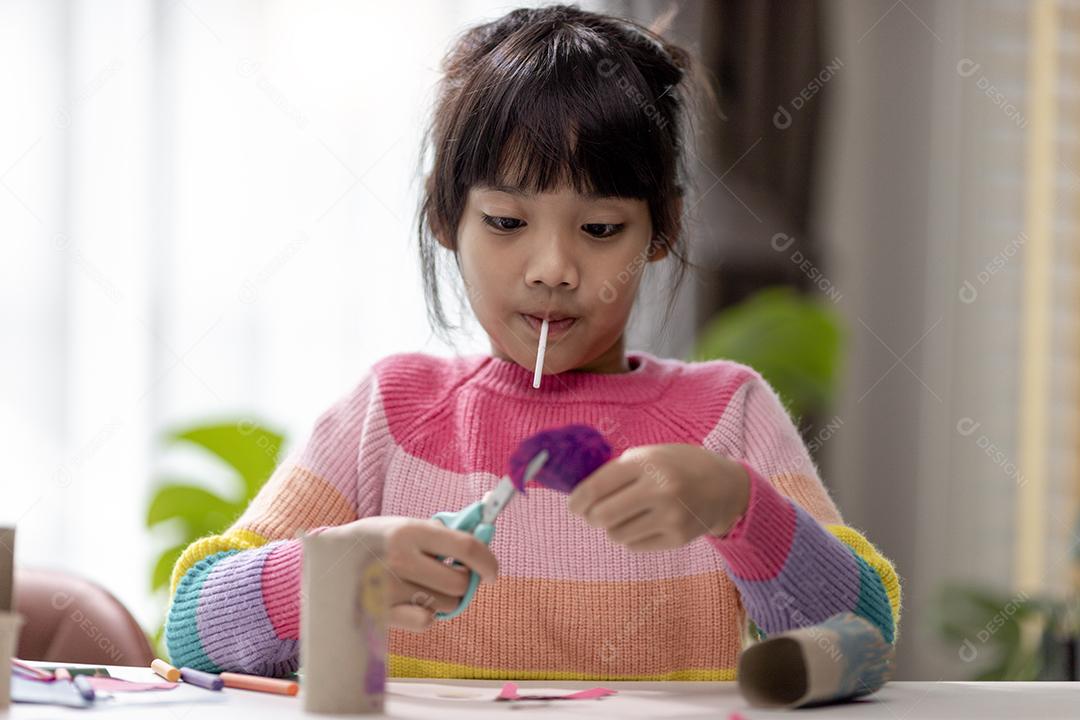 Retrato de uma menina asiática cortando um papel em atividades na aula de bricolage na School.Scissors corta papel.