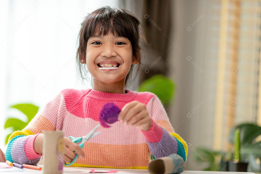 Retrato de uma menina asiática cortando um papel em atividades na aula de bricolage na School.Scissors corta papel.