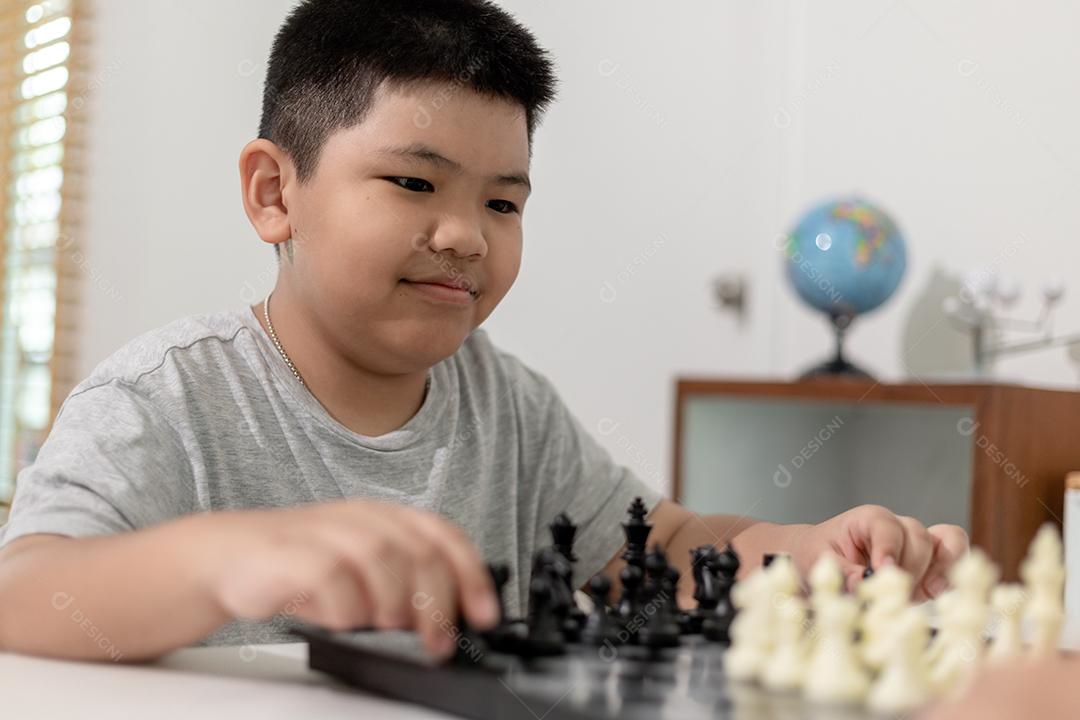 Menino e menina estão jogando xadrez em casa. Crianças jogando xadrez