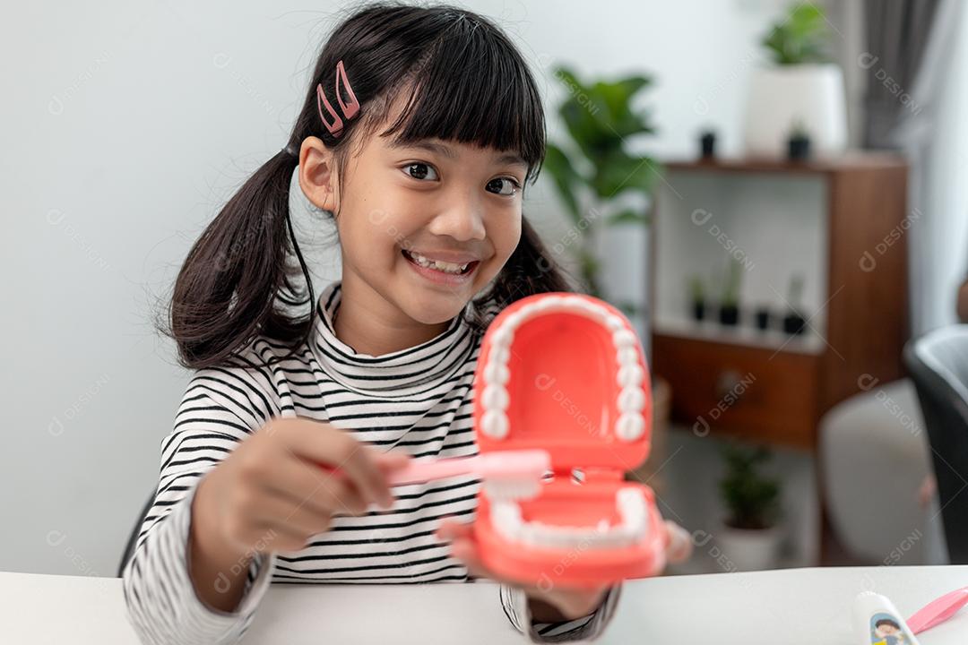 Uma criança pequena brinca com mandíbulas artificiais. Odontologia infantil.