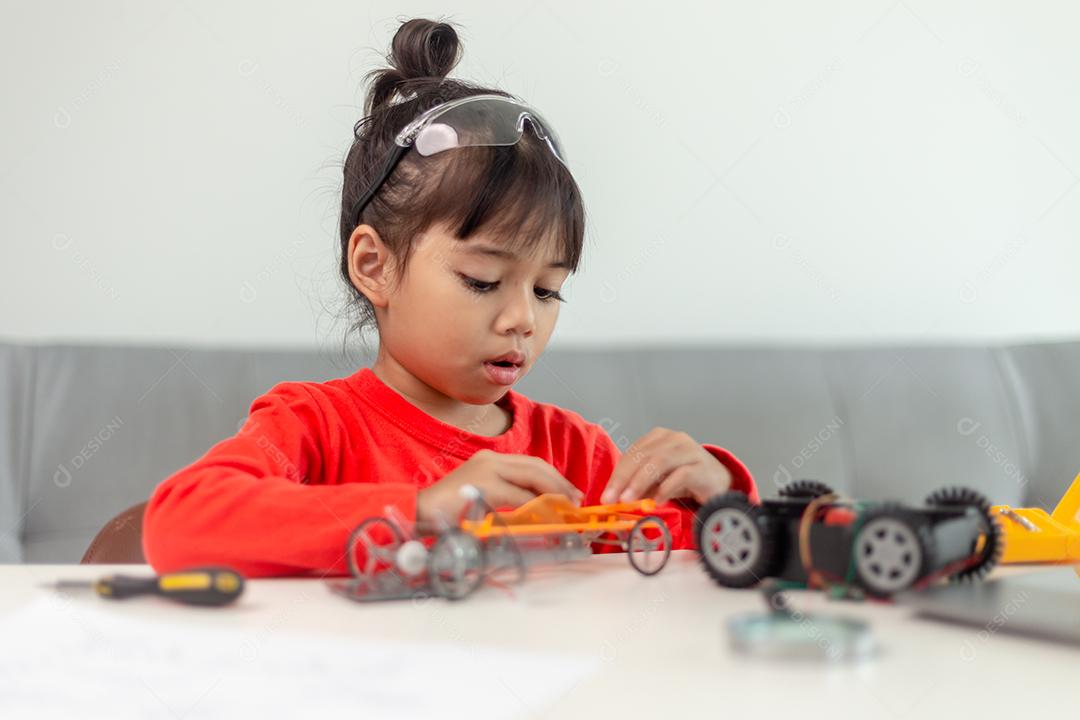 A garotinha está aprendendo a usar massinha colorida em uma sala bem iluminada