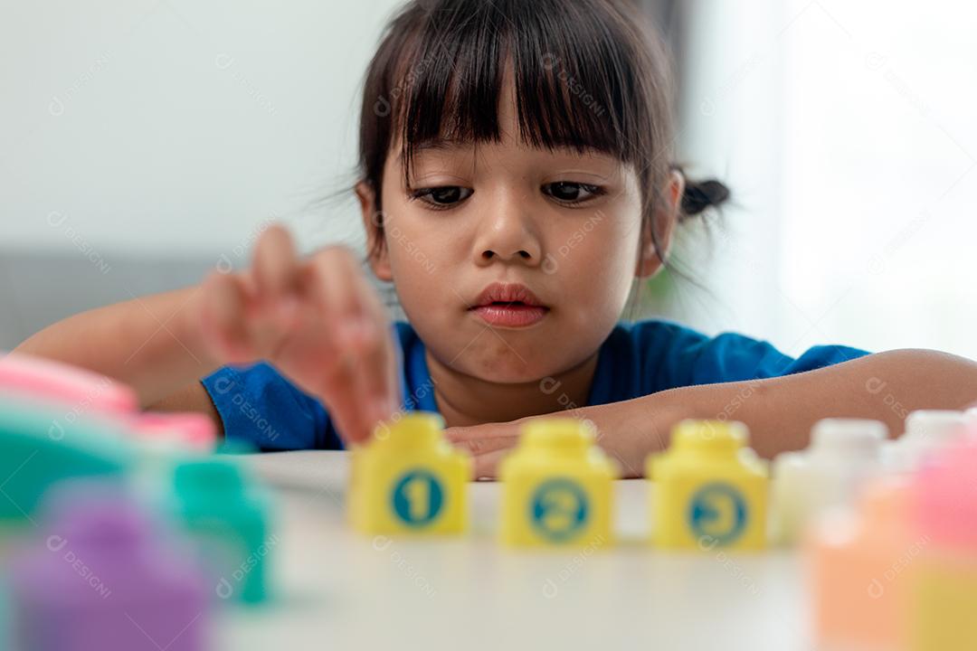 Adorável menina jogando blocos de brinquedo em uma sala iluminada