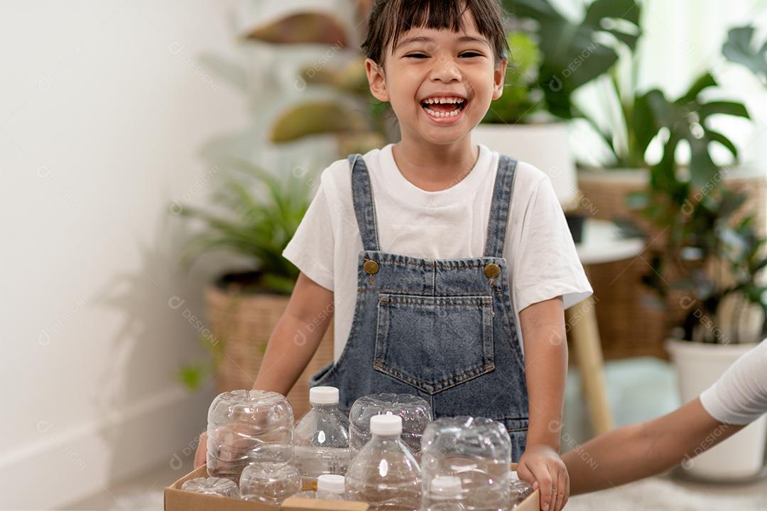 Garota olhando para a câmera e segurando garrafas plásticas para reciclagem