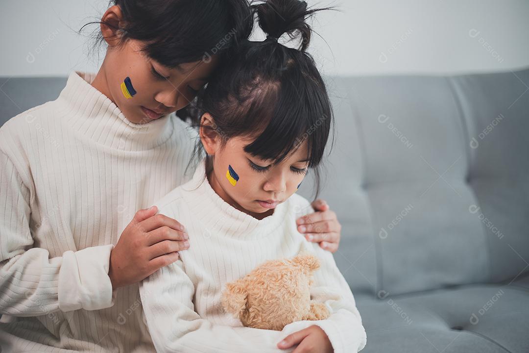 Uma criança com a bandeira da Ucrânia está chorando. Tristeza desejando esperança. As lágrimas das crianças da guerra. Evacuação de civis. Liberdade para a Ucrânia
