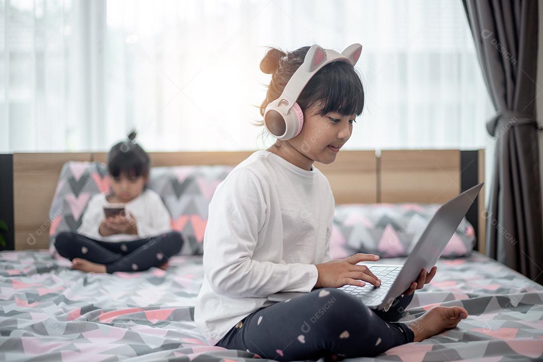 Menina asiática usando um laptop enquanto estava deitado na cama