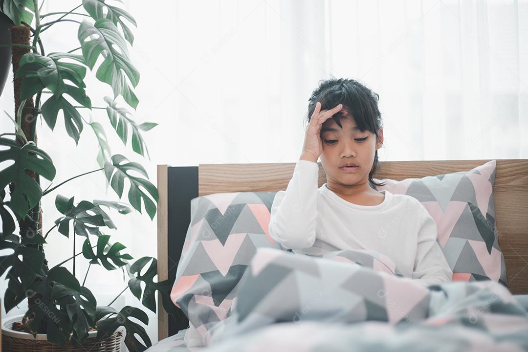 Uma garotinha está gripada, fica em casa debaixo de um cobertor, sua cabeça dói