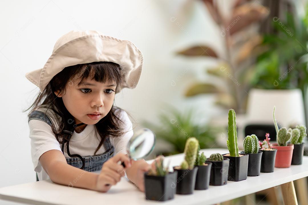 garoto toca suavemente o novo caule do cacto que ele cresce com cuidado, uma mão segura lupa. Educação da natureza, Montessori e conceito de habilidades de observação.