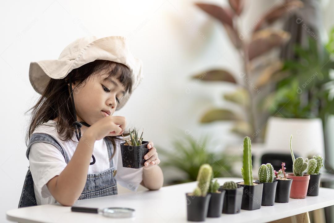 garoto toca suavemente o novo caule do cacto que ele cresce com cuidado, uma mão segura lupa. Educação da natureza, Montessori e conceito de habilidades de observação.