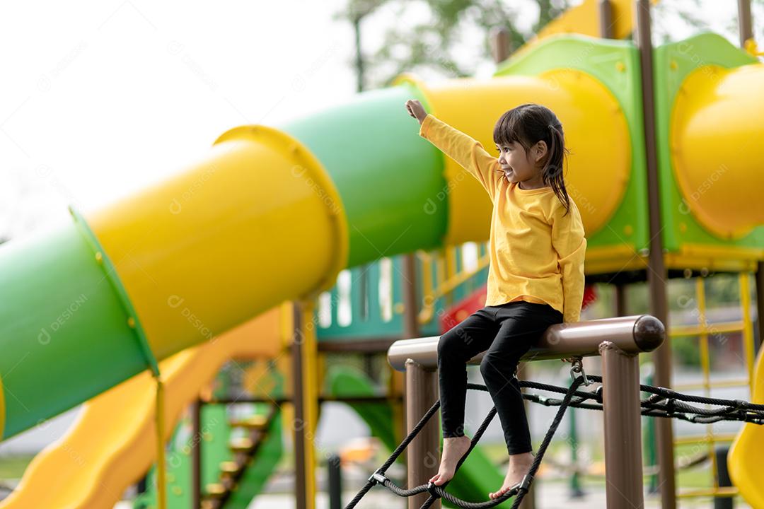 Menina asiática brincando no playground no parque ao ar livre Momento feliz e boa emoção