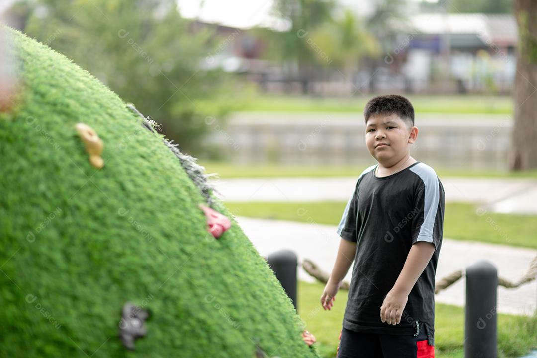 Criança brincando no playground ao ar livre. As crianças brincam na escola ou no jardim de infância. Garoto ativo no escorregador colorido e balanço. Atividade de verão saudável para crianças. Garotinho escalando ao ar livre.