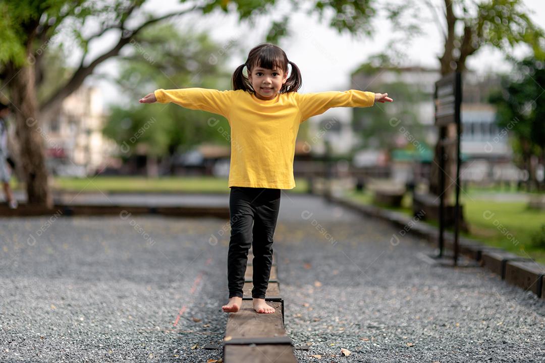 Menina asiática brincando no playground no parque ao ar livre Momento feliz e boa emoção