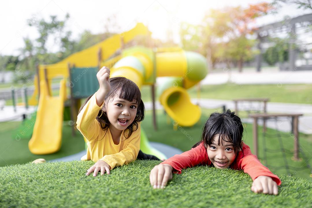 Criança brincando no playground ao ar livre. As crianças brincam na escola ou no jardim de infância. Garoto ativo no escorregador colorido e balanço. Atividade de verão saudável para crianças. Menina escalando ao ar livre.