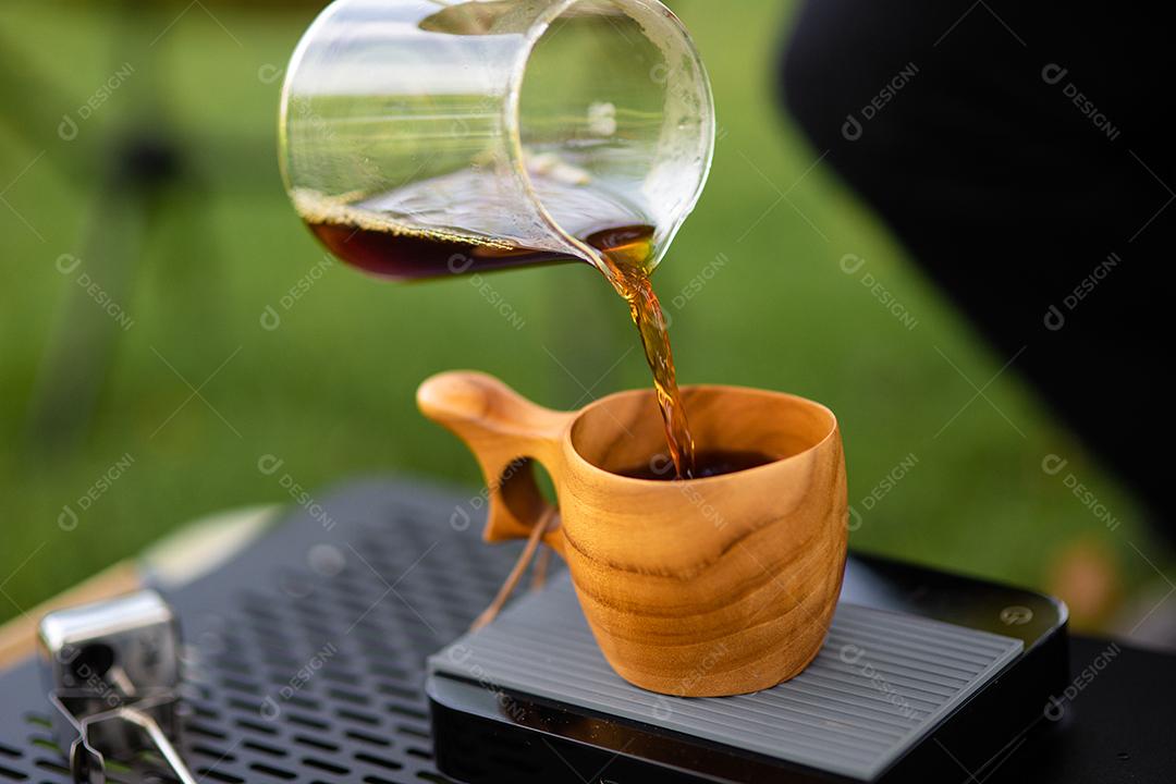 Jovem derramando café na xícara, café da manhã ao ar livre. viajante acampando pela primeira vez, nova experiência para descansar com barraca. Natureza, lazer, sem pressa, conceito de paz e tranquilidade