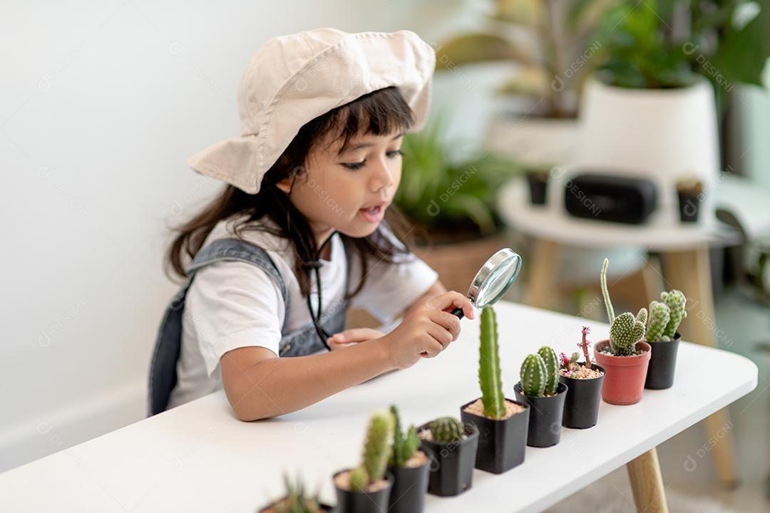 boy gently touches the new stem of the cactus he grows carefully, a hand holds magnifying glass. Nature education, Montessori and observation skills concept.
