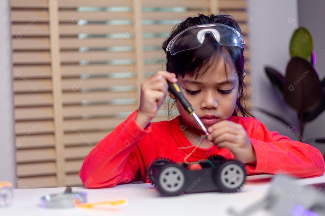 Os alunos da Ásia aprendem em casa na codificação de carros robóticos e cabos de placas eletrônicas em STEM, STEAM, código de computador de tecnologia de ciência de engenharia matemática em robótica para o conceito de crianças.