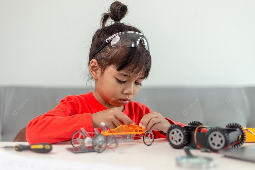 Os alunos da Ásia aprendem em casa na codificação de carros robóticos e cabos de placas eletrônicas em STEM, STEAM, código de computador de tecnologia de ciência de engenharia matemática em robótica para o conceito de crianças.