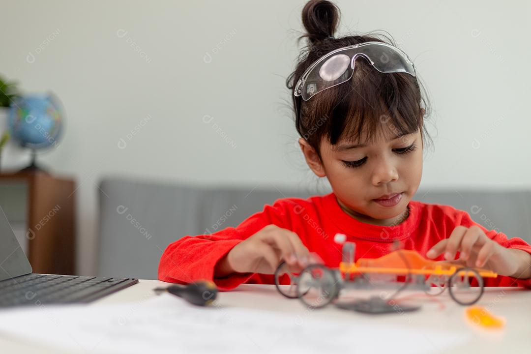 Os alunos da Ásia aprendem em casa na codificação de carros robóticos e cabos de placas eletrônicas em STEM, STEAM, código de computador de tecnologia de ciência de engenharia matemática em robótica para o conceito de crianças.