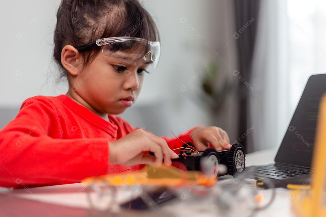 Os alunos da Ásia aprendem em casa na codificação de carros robóticos e cabos de placas eletrônicas em STEM, STEAM, código de computador de tecnologia de ciência de engenharia matemática em robótica para o conceito de crianças.