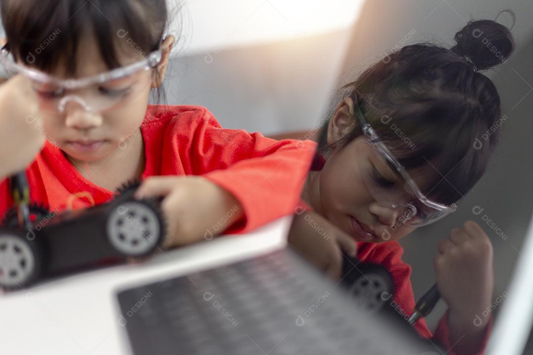 Os alunos da Ásia aprendem em casa na codificação de carros robóticos e cabos de placas eletrônicas em STEM, STEAM, código de computador de tecnologia de ciência de engenharia matemática em robótica para o conceito de crianças.