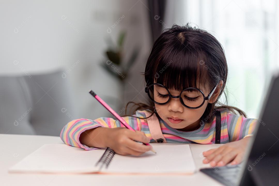 Aluna asiática estuda aulas on-line de aprendizagem on-line com o professor, Garota feliz aprende inglês on-line com tablet em casa. Novo normal.Covid-19 coronavirus.Distanciamento social. fique em casa