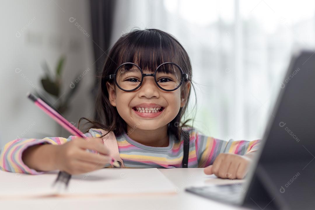 Aluna asiática estuda aulas on-line de aprendizagem on-line com o professor, Garota feliz aprende inglês on-line com tablet em casa. Novo normal.Covid-19 coronavirus.Distanciamento social. fique em casa