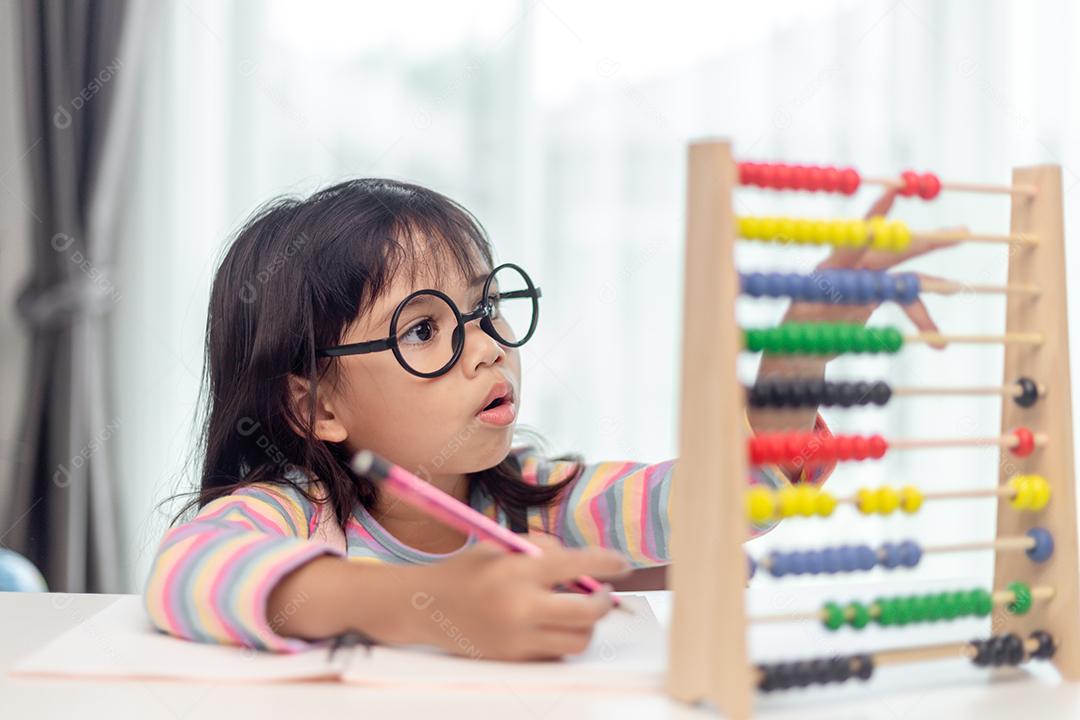 Uma jovem asiática fofa está usando o ábaco com contas coloridas para aprender a contar em casa
