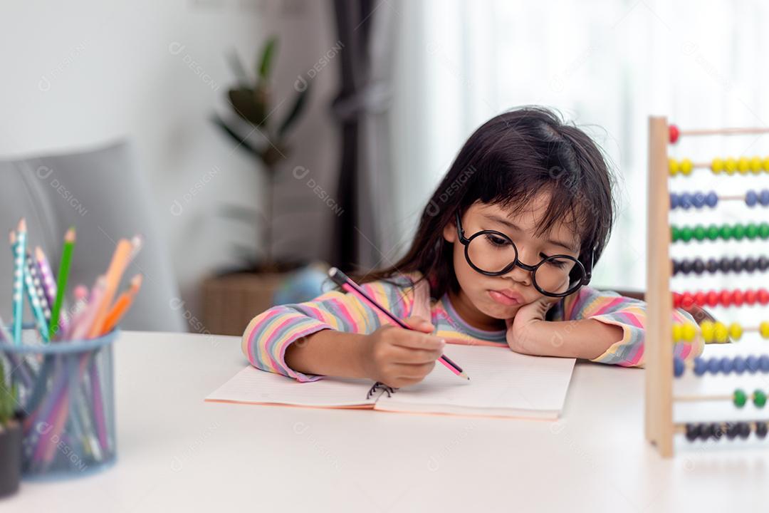 Uma jovem asiática fofa está usando o ábaco com contas coloridas para aprender a contar em casa